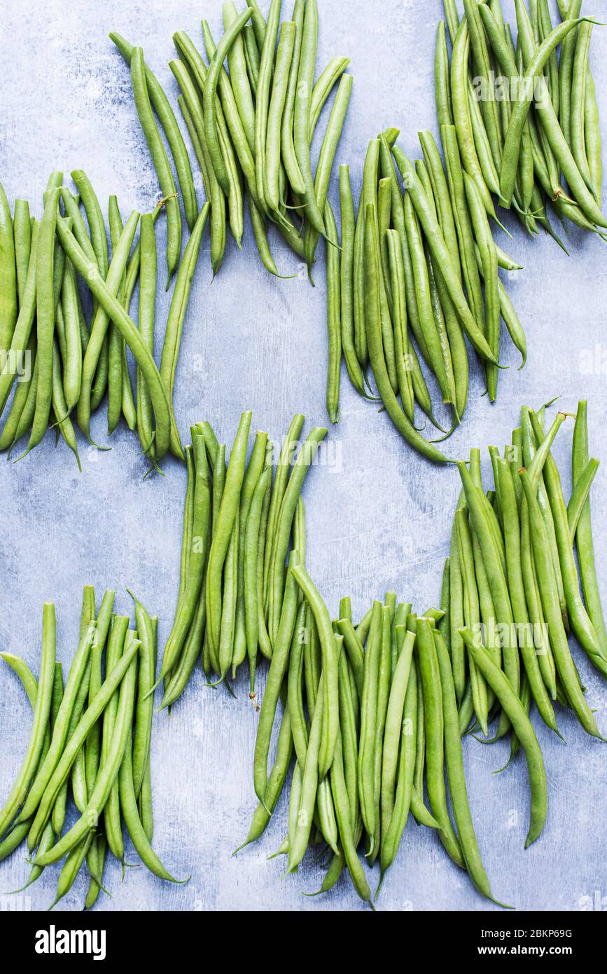 Trauben von grünen Bohnen auf grauem Hintergrund. Stockfoto
