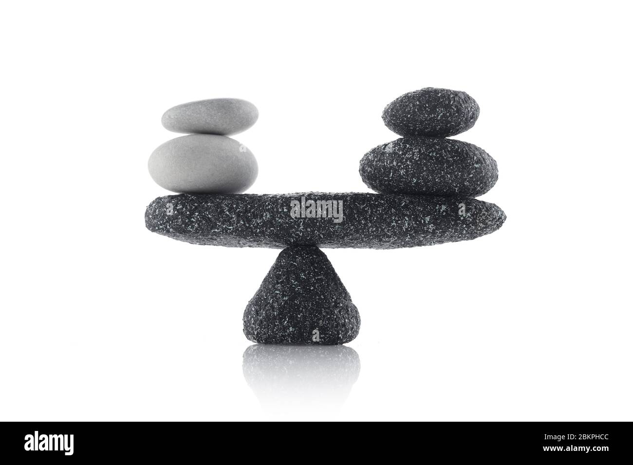 Ausbalancierende schwarze und weiße Steine auf weißem Hintergrund isoliert Stockfoto