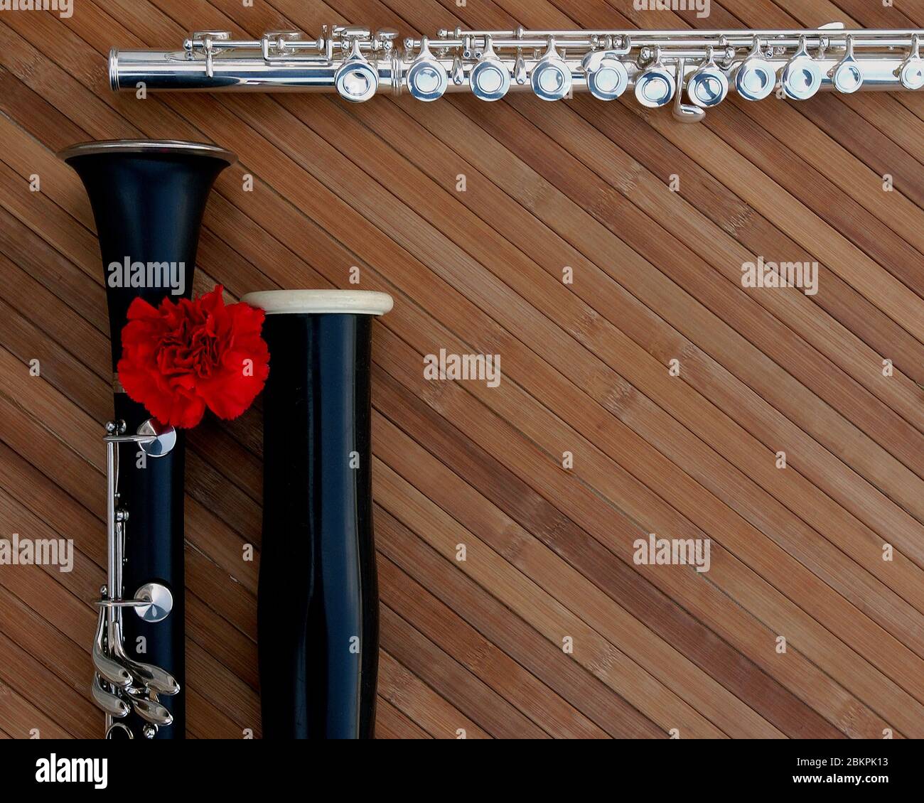 Oboe, Klarinette und Flöte auf einer Holztafel mit roter Blume. Stockfoto