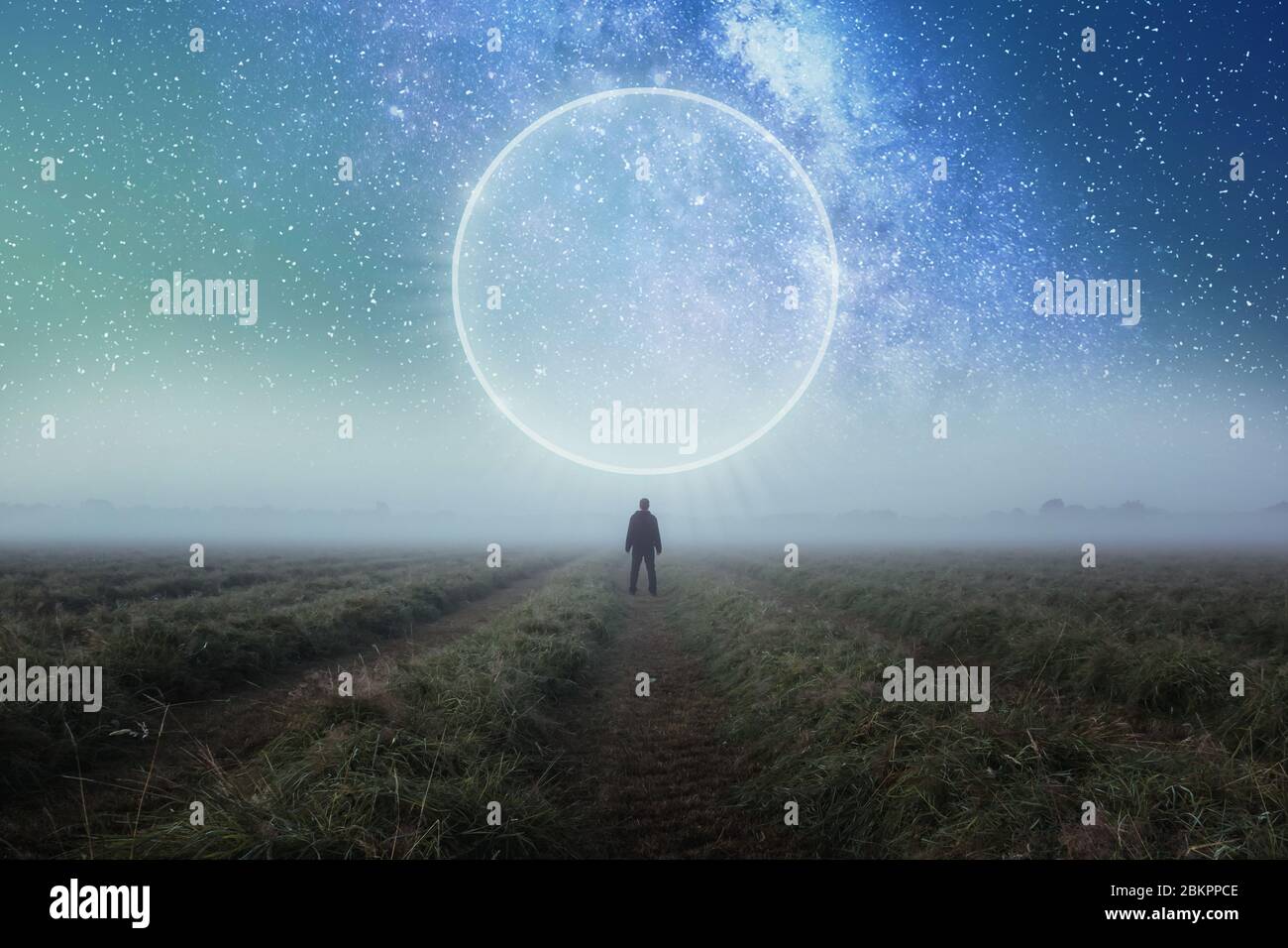 Ein Science-Fiction-Konzept. Ein Mann, der in einem Feld steht und über den Raum blickt, mit einem glühenden Portal am Nachthimmel Stockfoto