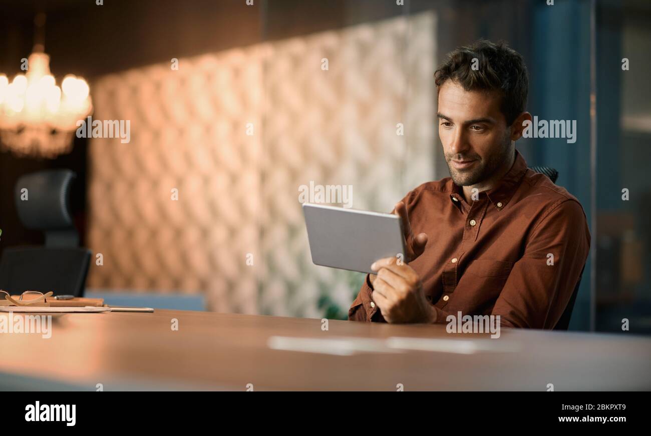 Geschäftsmann, der außerhalb der Geschäftszeiten auf einem Tablet arbeitet Stockfoto