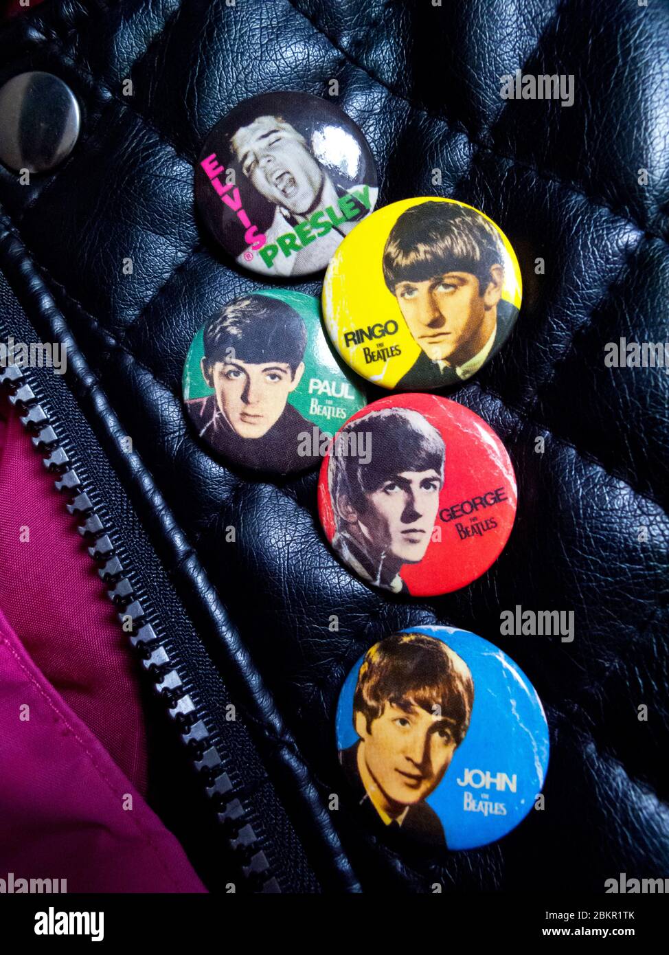 Lederjacke mit Abzeichen der Beatles John Lennon Paul McCartney George Harrison und Ringo Starr neben einem Abzeichen mit Elvis Presley. Stockfoto