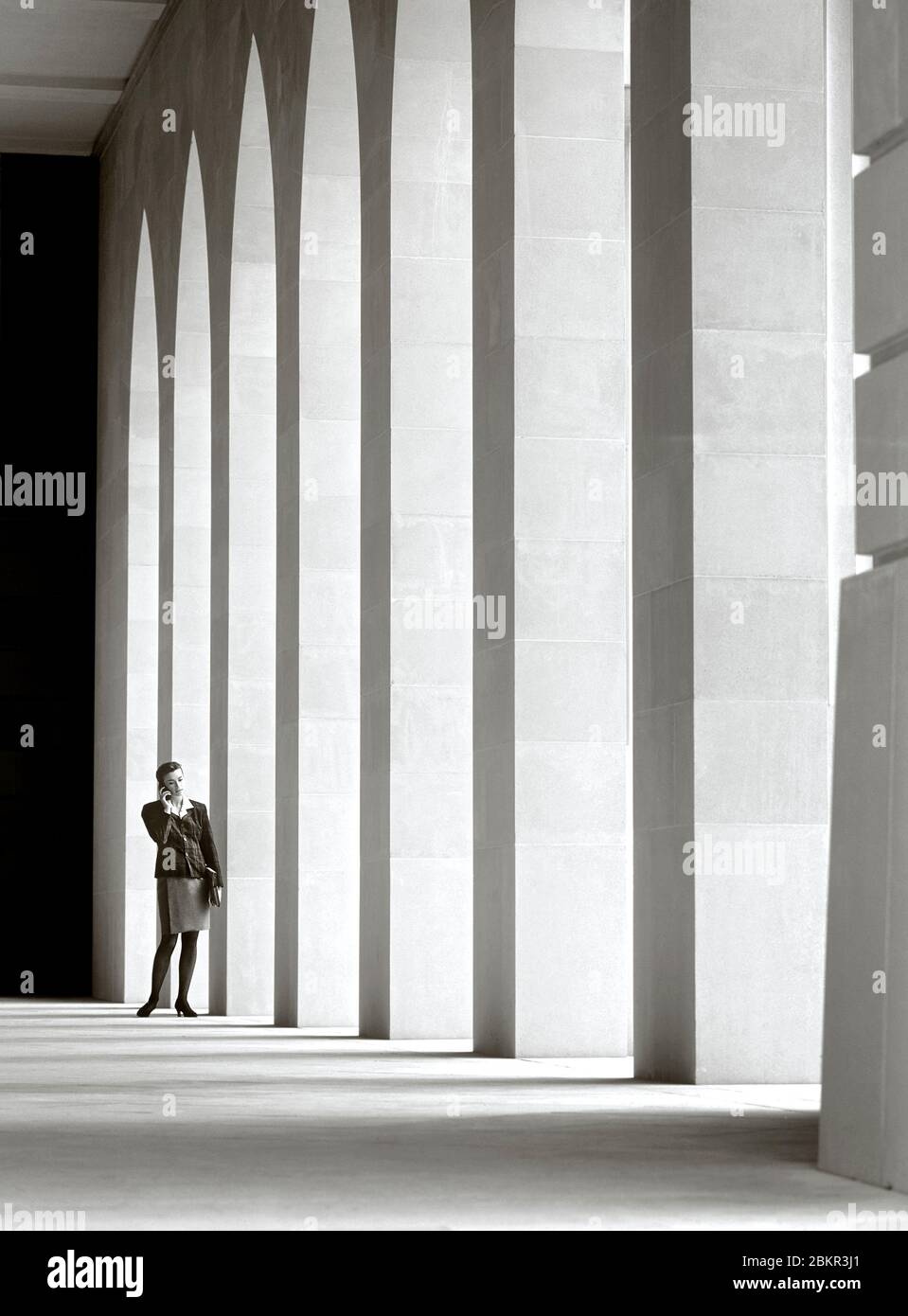 Weibliche Geschäftsführerin 25-30 Jahre in der Stadt Umgebung draußen sprechen auf ihrem Handy in ruhigen Atrium Stein Architektur Umgebung Stockfoto