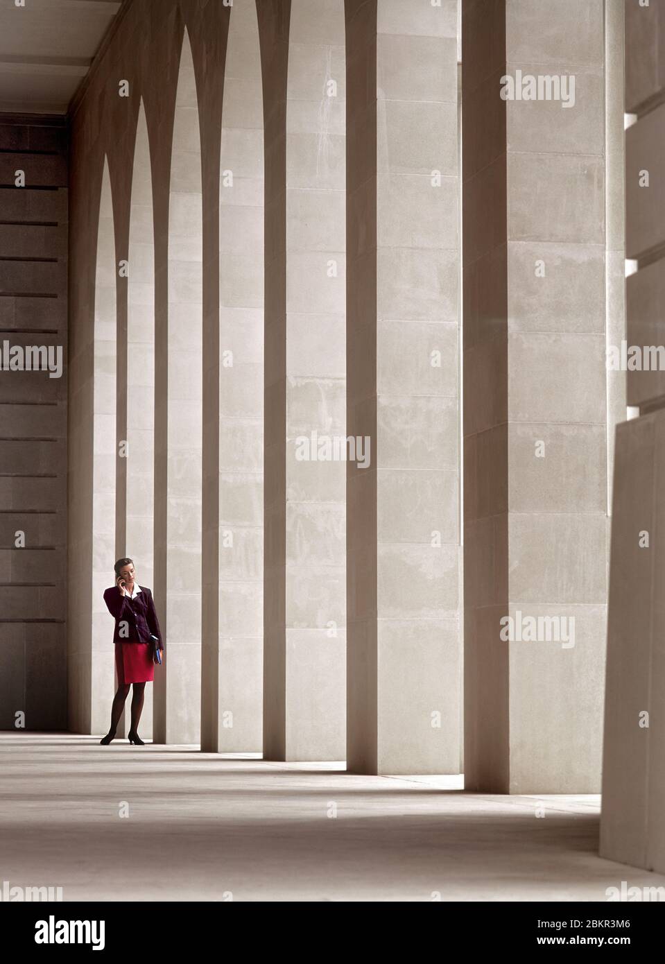 Weibliche Geschäftsführerin 25-30 Jahre in der Stadt Umgebung draußen sprechen auf ihrem Handy in ruhigen Atrium Stein Architektur Umgebung Stockfoto