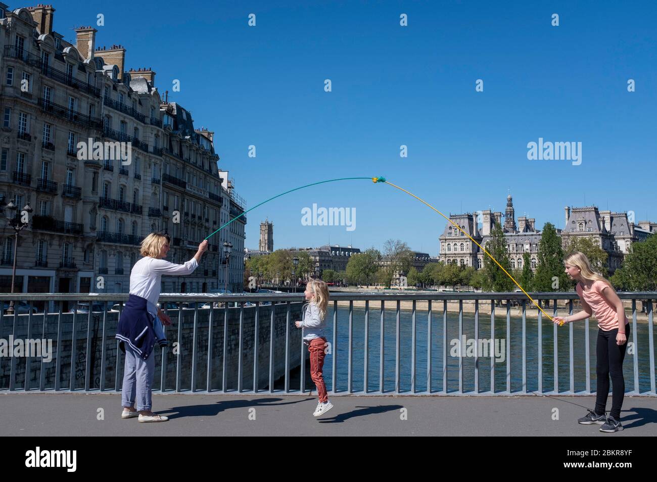 Frankreich, Paris, COVID-19 (oder Coronavirus) Sperrung, Saint-Louis-Brücke, Familie spielen mit Springseil Stockfoto