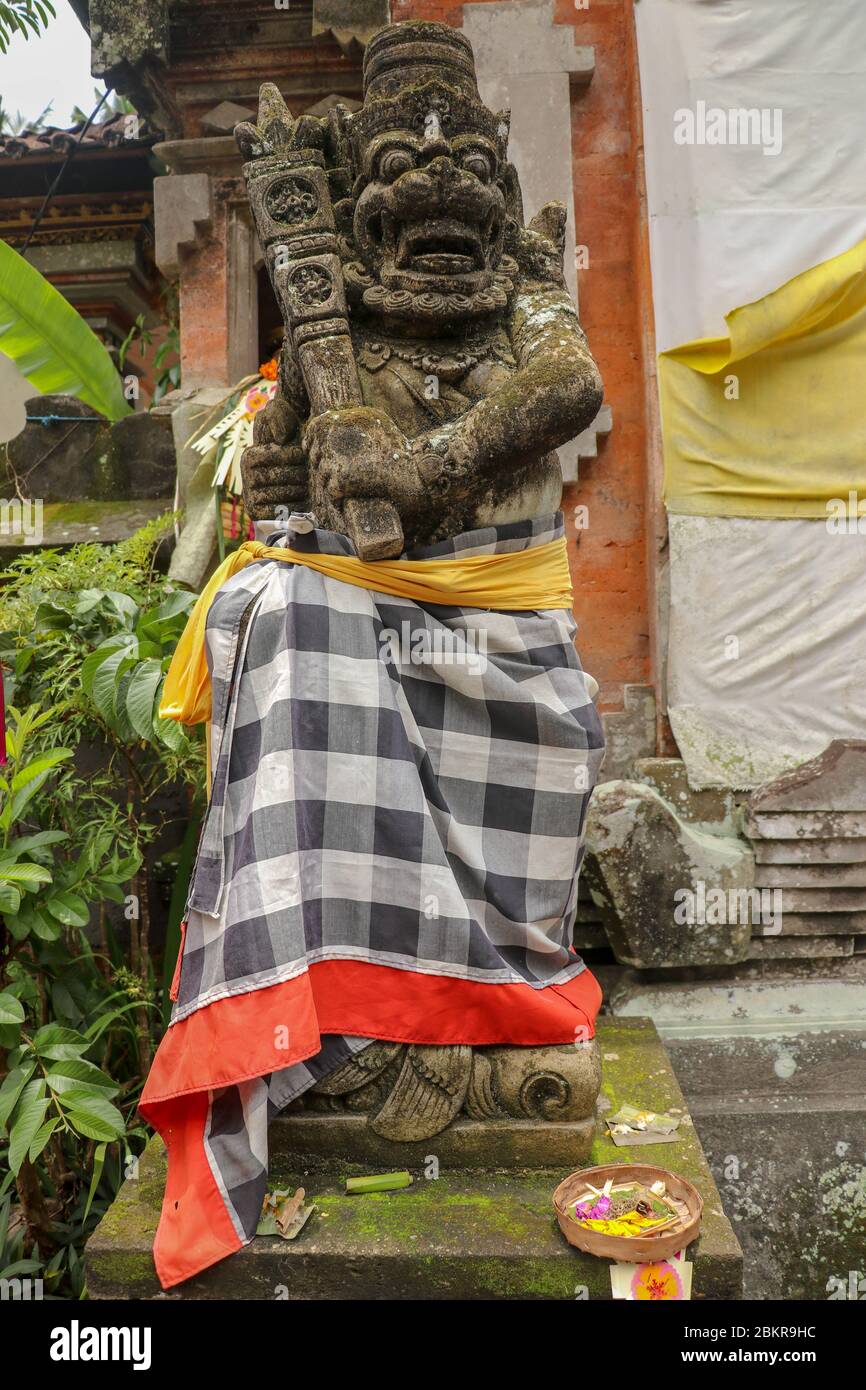 Ein gemauert Eingangstor zu einem Hindu-Tempel auf Bali, Indonesien. Eingangstor ist geschlossen. Daneben ist eine Schutzfigur, eingewickelt in karierte Materie Stockfoto