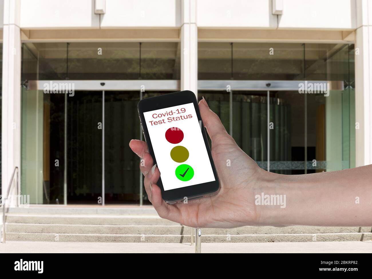 Modell des Eingangs zum Büro mit Hand halten Smartphone-App zeigt Immunität gegen Coronavirus Stockfoto