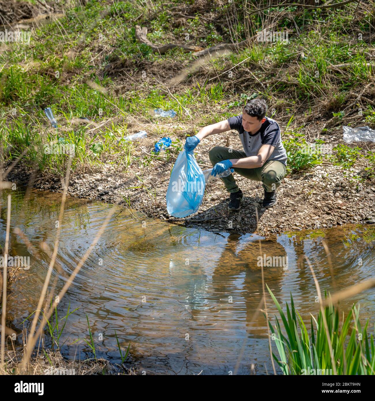 Reinigung von Plastikmüll am Flussufer durch einen Freiwilligen. Der Natur und dem Umweltschutz zu helfen Stockfoto