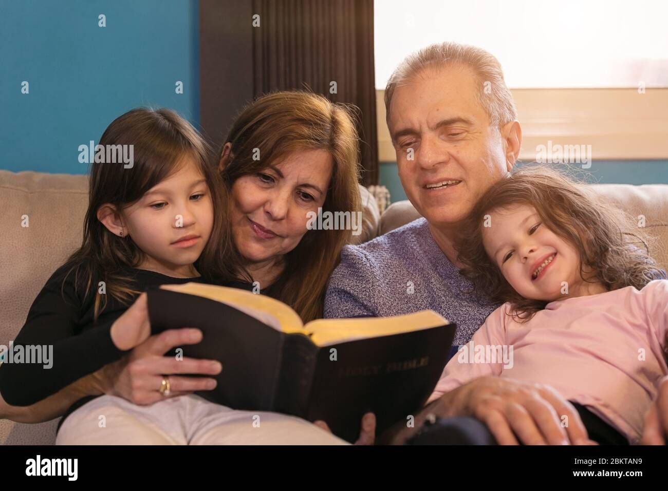 Großeltern, die Enkelkinder über die Heilige Bibel unterrichten Stockfoto