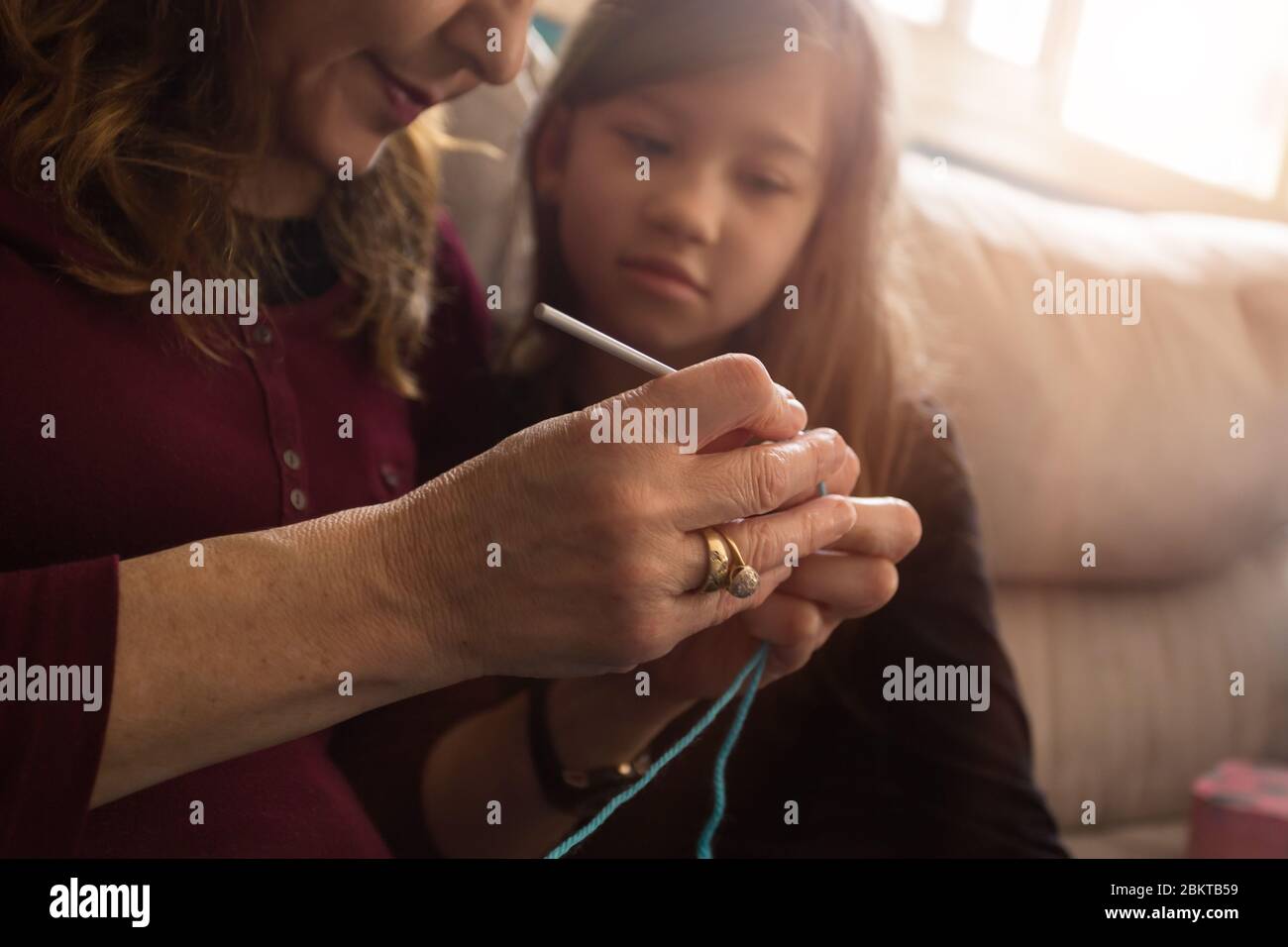 Die liebevolle Großmutter lehrt ihre kleine Enkelin, wie man stricken soll Stockfoto