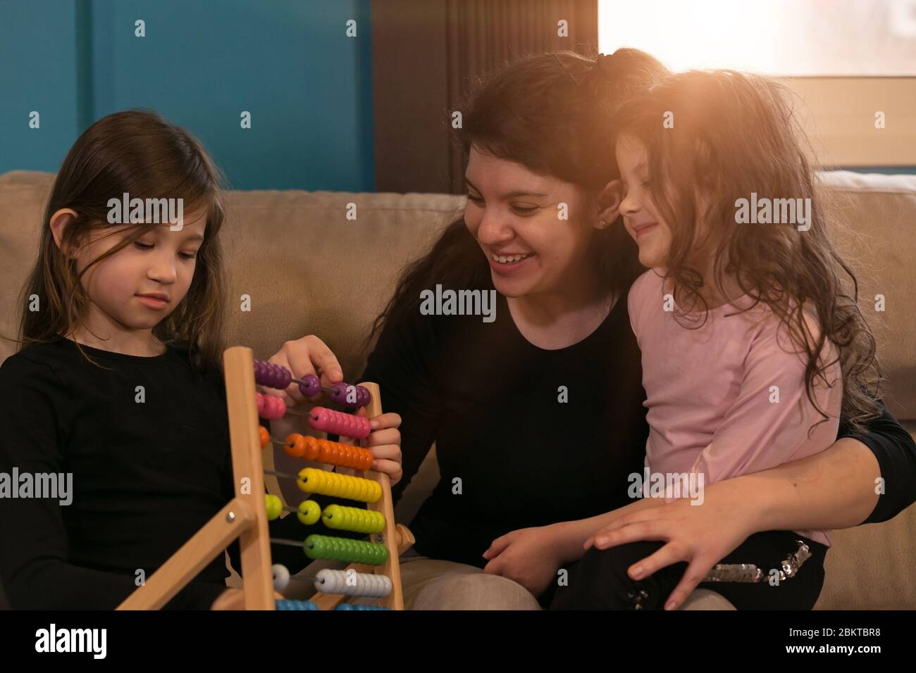 Junge Mutter Lehre ihre kleinen Töchter Mathematik aus ihrem Wohnzimmer Stockfoto