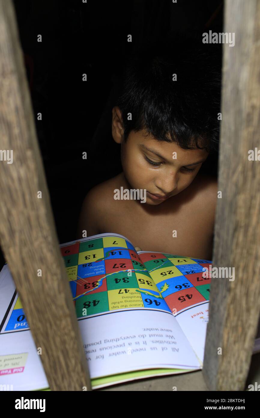 Kinderporträt vor dem Fenster. Trauriger kleiner Junge gezwungen, zu Hause zu bleiben, wie das pandemische Coronavirus, covid19. Der Junge liest einsam im Zimmer. Stockfoto
