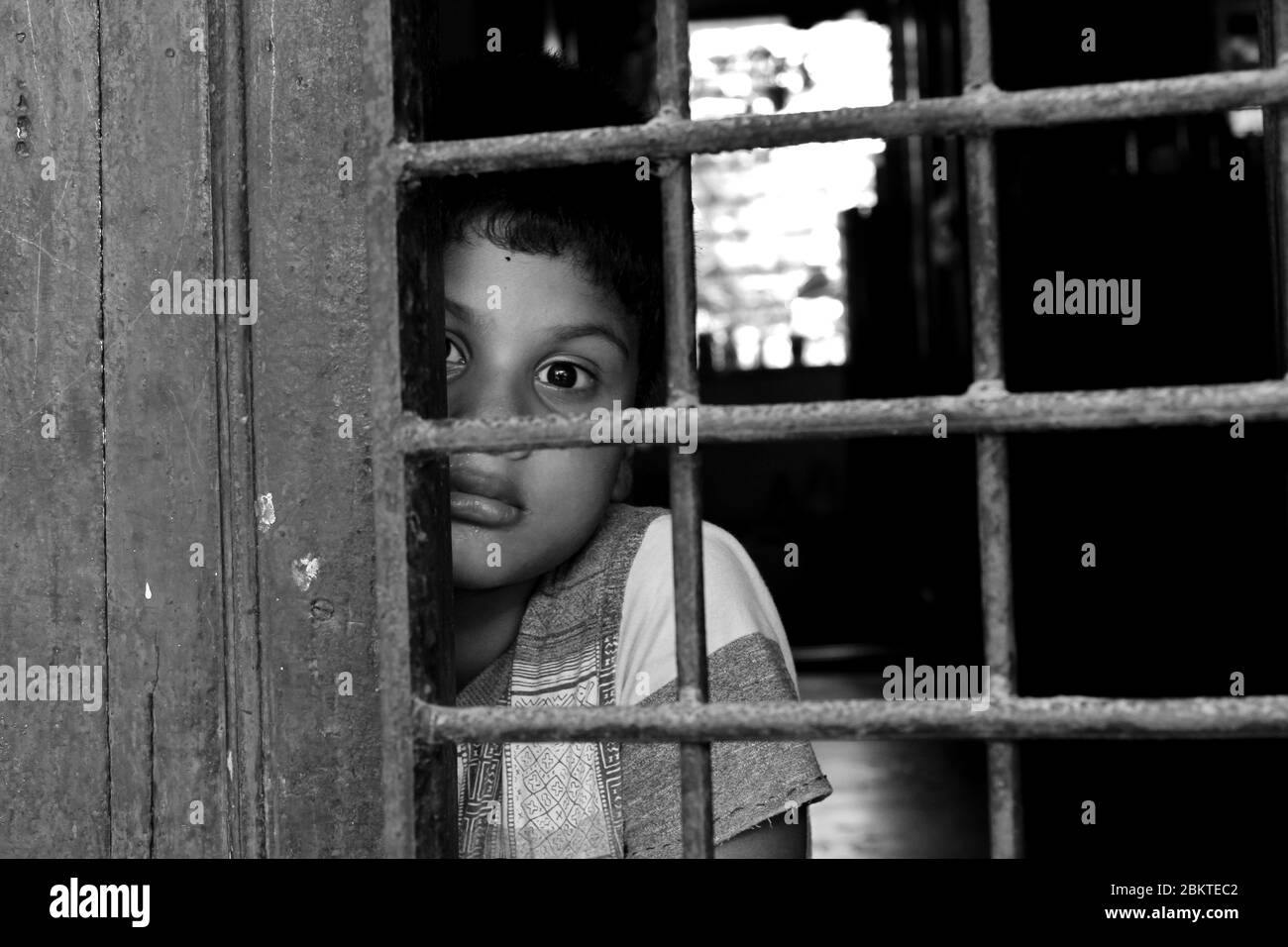 Kinderporträt vor dem Fenster. Kind Auge neugierig in die Welt schauen. Trauriger kleiner Junge, der als pandemischer Coronavirus zu Hause bleiben musste Stockfoto