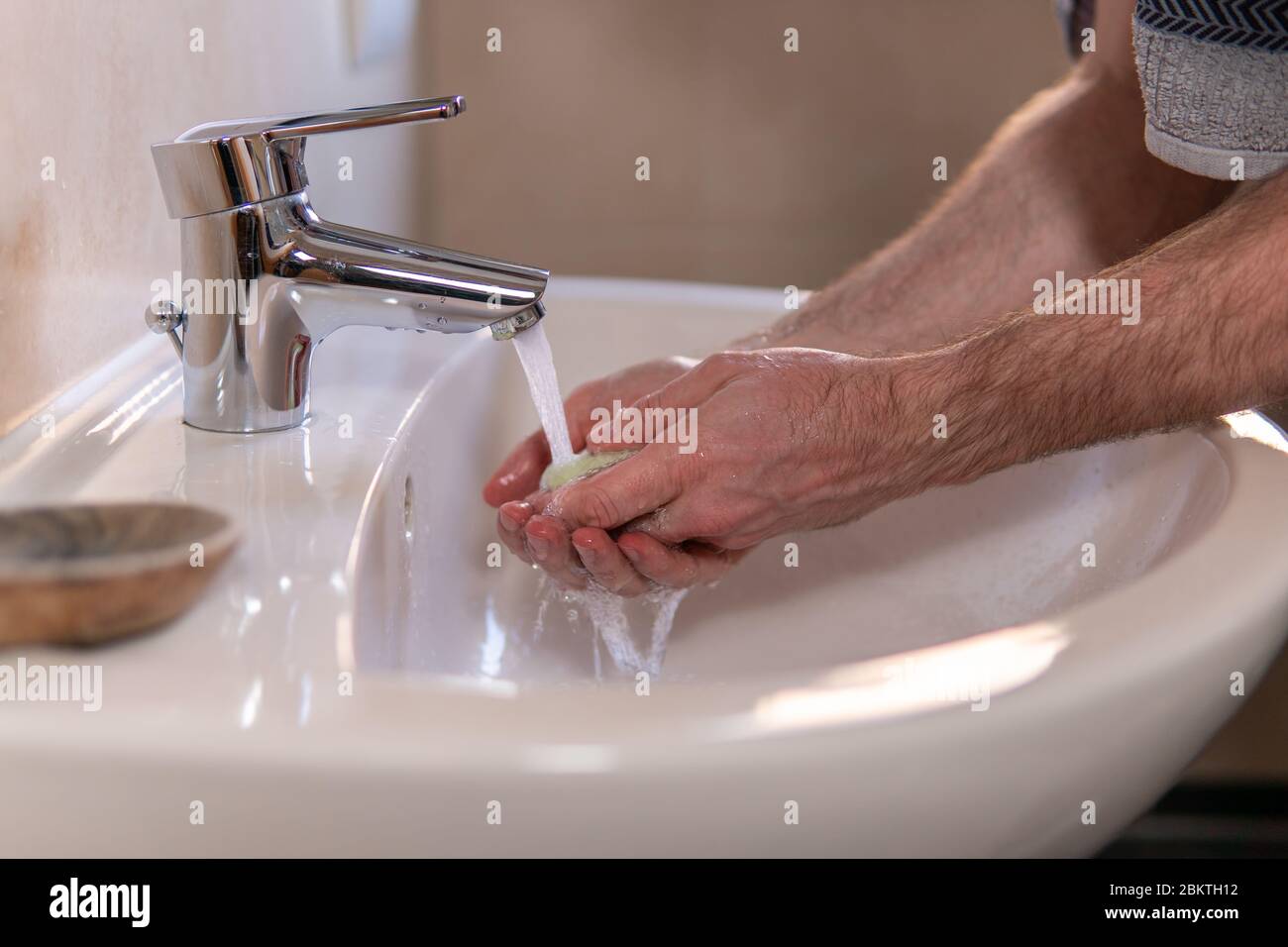 Hand des kaukasischen Mannes, der antibakterielle Seife unter fließendem Wasserhahn hält. Händewaschen, Körperhygiene, Händedesinfektion zur Vorbeugung von Krankheiten Stockfoto