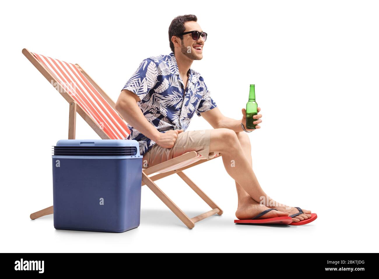 Lächelnder junger Mann mit einer Flasche Bier auf einem Liegestuhl mit  einer Kühlbox auf weißem Hintergrund isoliert sitzen Stockfotografie - Alamy