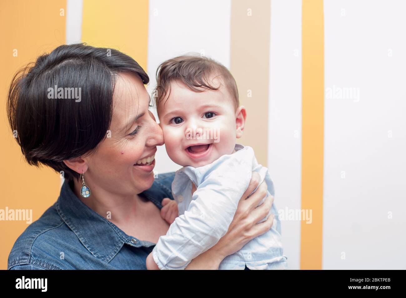 Vorderansicht einer jungen Mutter, die ihr Baby schön hält, beide lächeln. Großer Kopierplatz Stockfoto