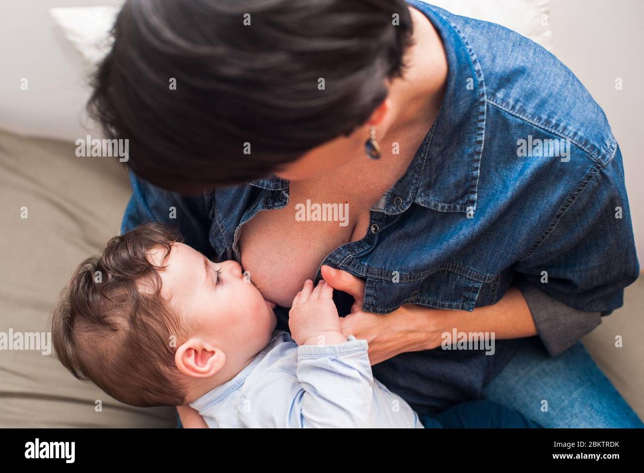 Tägliche Routine. Aus einem hohen Winkel betrachtet, wie eine Mutter ihren Jungen hält und stillt. Stockfoto