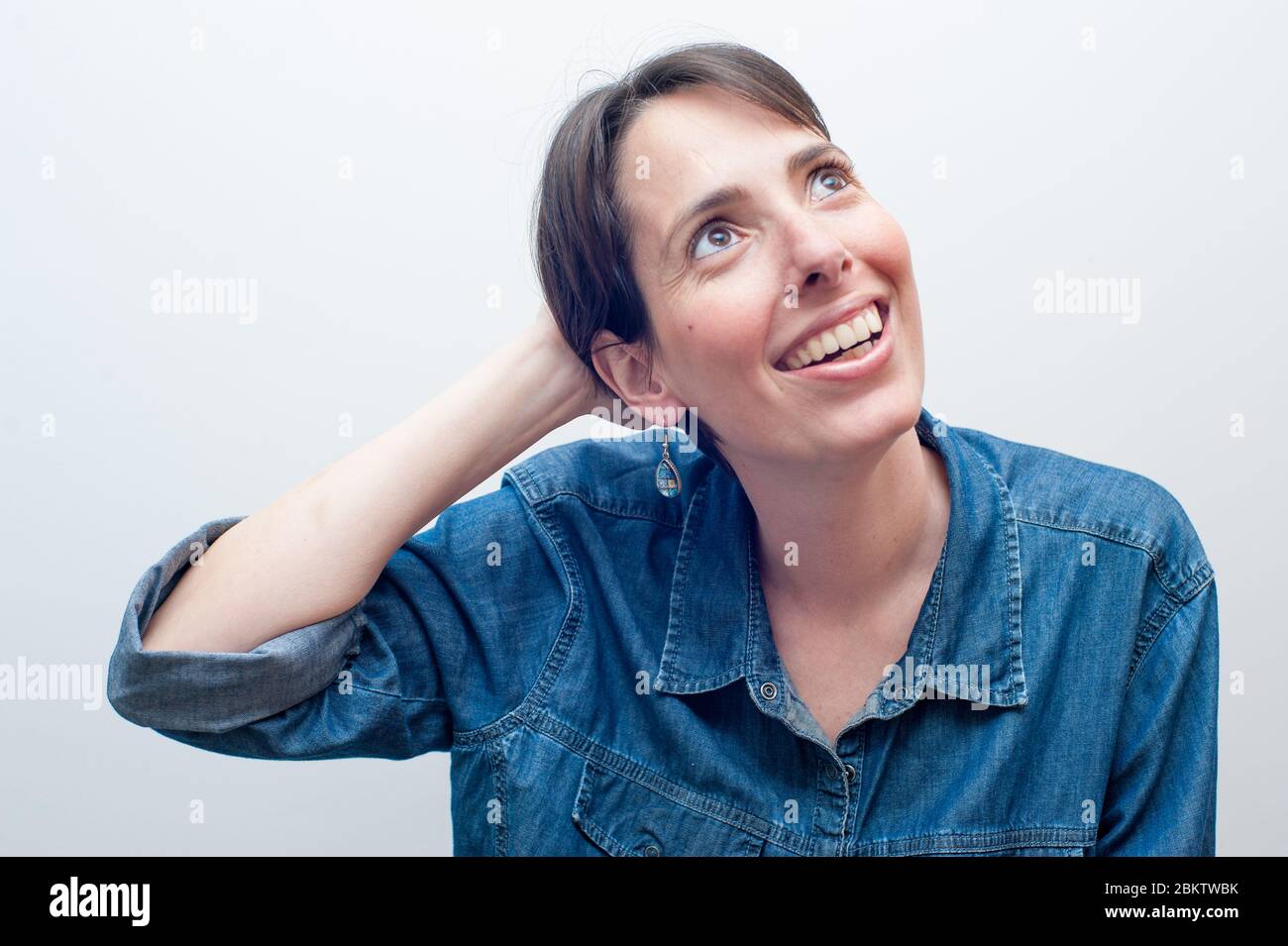 Junge schöne Frau in blauen Jeans lächelnd mit ihrer rechten Hand auf ihrem Hals schauen. Großer Kopierplatz Stockfoto