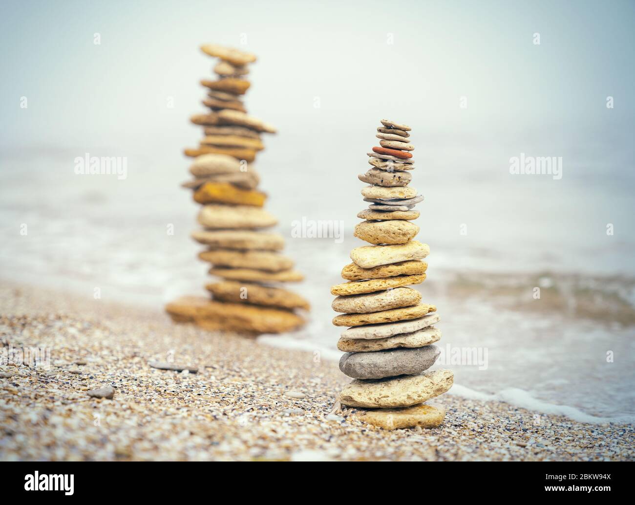 Steinpyramide auf Sand symbolisiert Zen, Harmonie, Gleichgewicht. Positive Energie. Ozean im Hintergrund Stockfoto