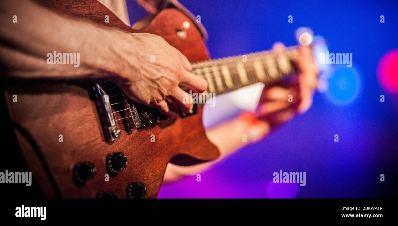 Ein Musiker Gitarrist, der während eines Live-Konzerts eine elektrische Holzgitarre anklimmt Stockfoto