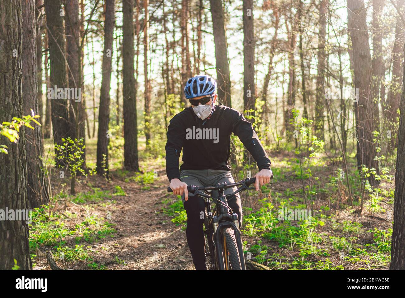 Radfahrer tragen Verschmutzungsmaske. Junger Mann in Atemschutzmaske mit  Filter PM 2.5 mit Fahrt auf dem Fahrrad im Park. Covid 19 Quarantäne Sport.  Mountainbiker fahren Stockfotografie - Alamy