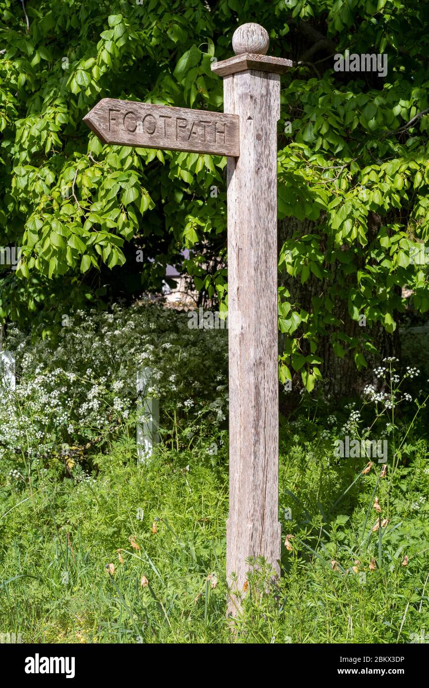 Holzpfadschild, das Wanderer zu einem öffentlichen Wanderweg in Swinbrook, The Cotswolds, Oxfordshire, Großbritannien, führt Stockfoto