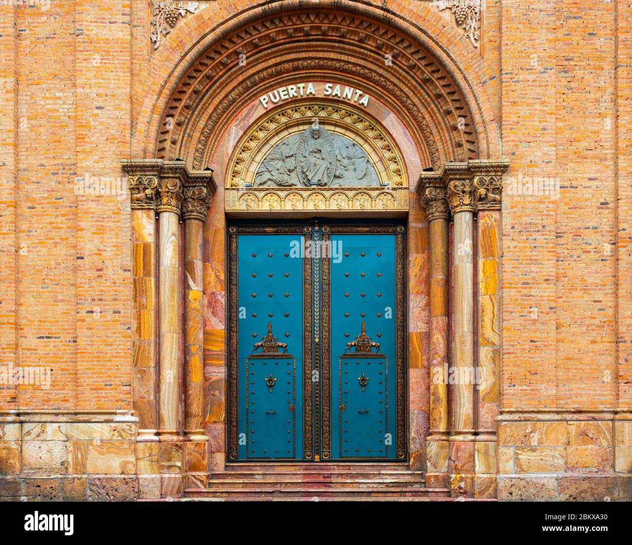 Eingang mit türkisfarbener Tür der Neuen Kathedrale in Cuenca, Ecuador. Übersetzung an der Tür: 'Puerta Santa' = 'Heilige Tür'. Stockfoto