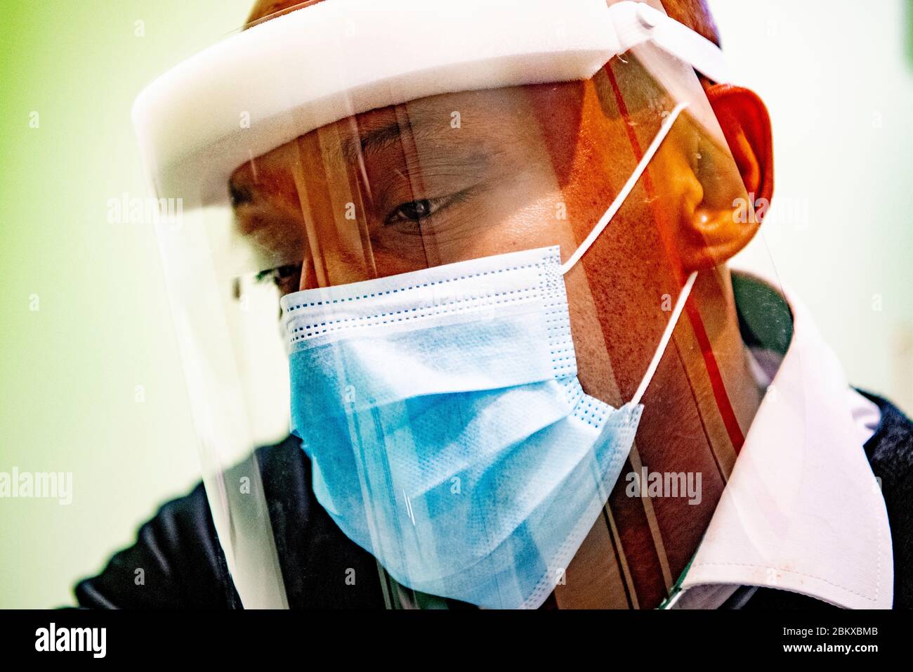 Ein Optiker, der bei der Wiedereröffnung vorsorglich einen Schutzschild und eine Maske trägt.durch Befolgung der Bedingungen der sozialen Distanzierung und Tragen einer Schutzmaske. Die niederländische Regierung erlaubte einigen Unternehmen, wieder zu öffnen. Stockfoto