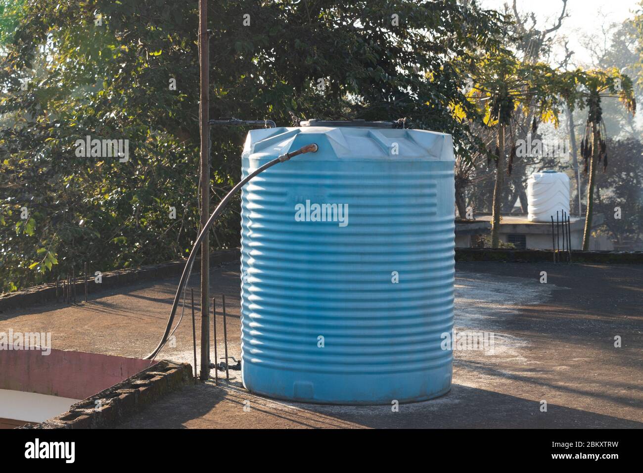 Blauer Wassertank auf der Terrasse des Hauses mit Stahlrohren verbunden platziert. Stockfoto