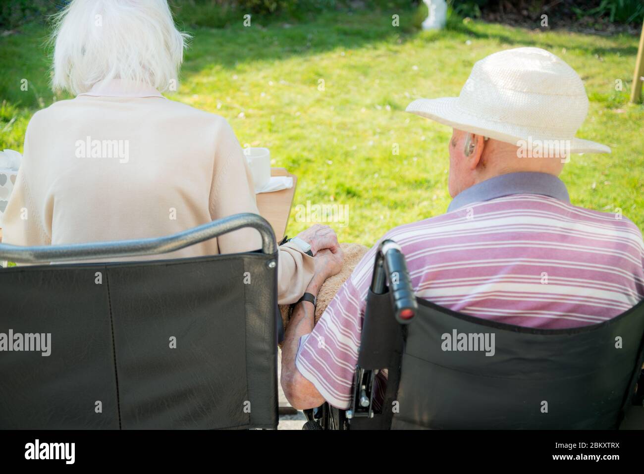 Ehemann und Ehefrau in ihren 90ern noch verliebt und die Frau hat Frühstadium Demenz.natürlich und ungestellt in ihrem Garten im Frühling. Stockfoto