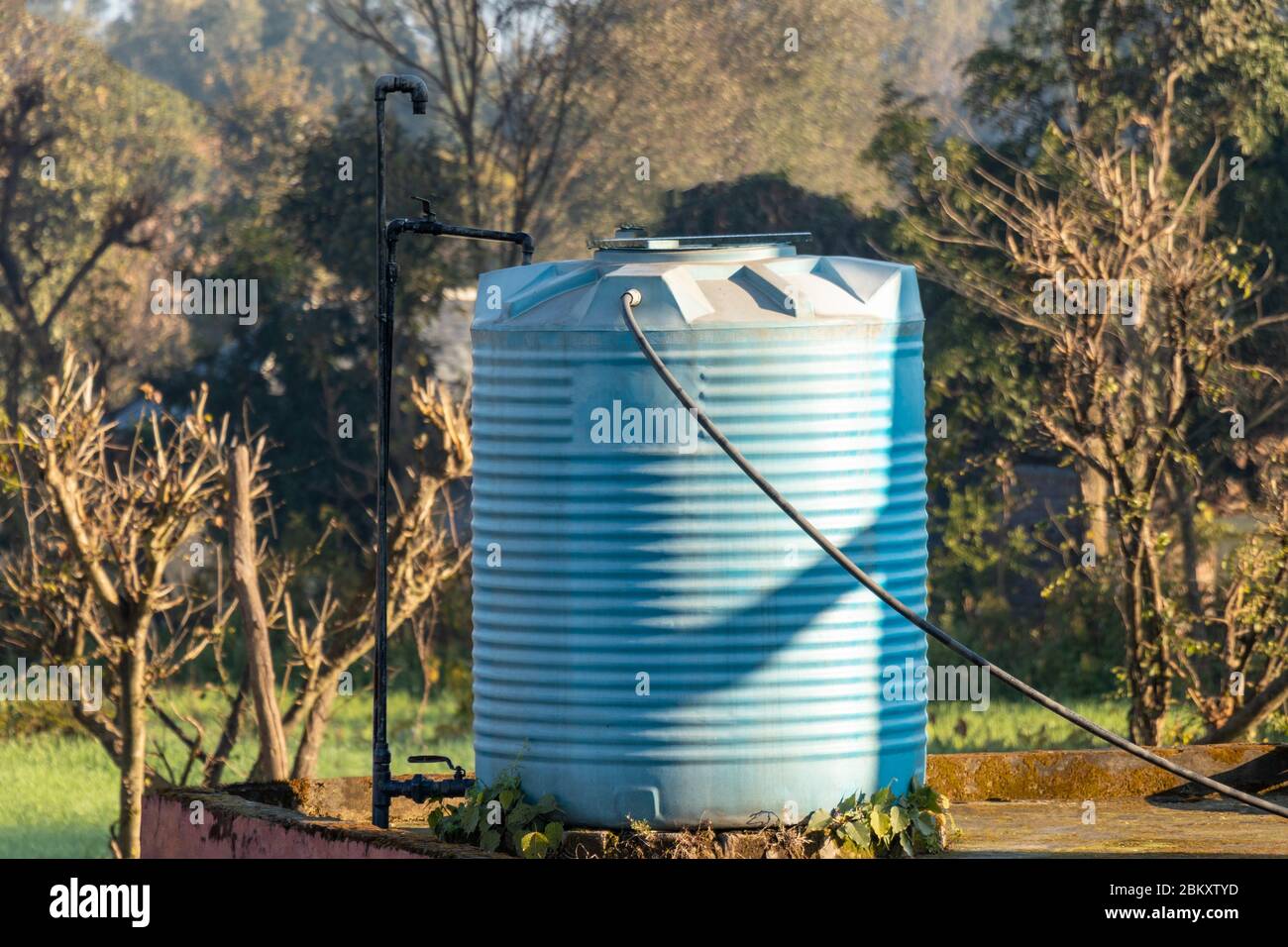 Blauer Wassertank auf der Terrasse des Hauses mit Stahlrohren verbunden platziert. Stockfoto