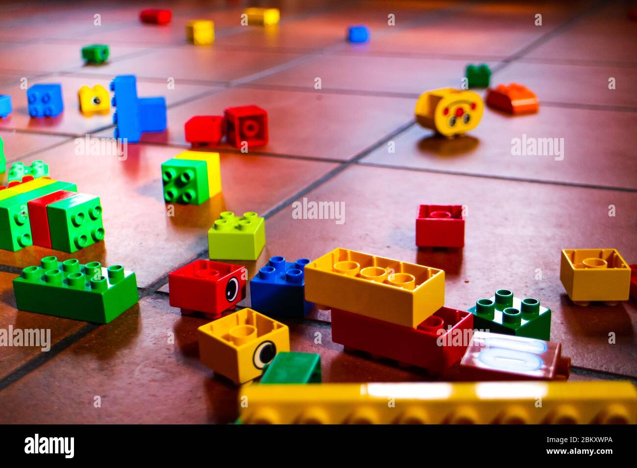 Bunte Lego Duplo Blöcke auf einem gefliesten Steinboden. Stockfoto