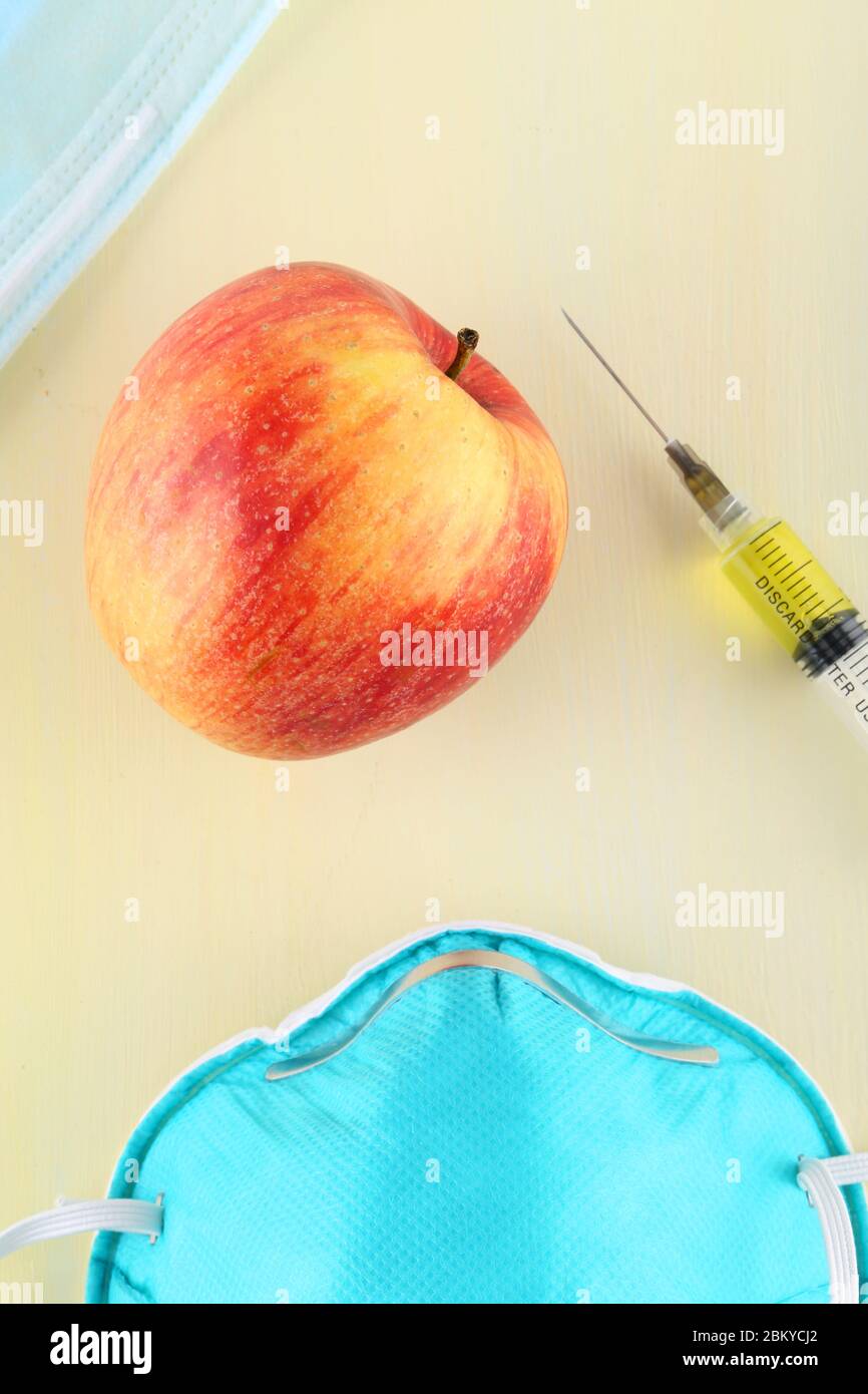 Chemische Zusatzstoffe in Lebensmitteln oder genetisch veränderte Frucht Konzept. Roter Apfel mit Spritzen von Chemikalien. Isoliert auf rotem Hintergrund. Stockfoto