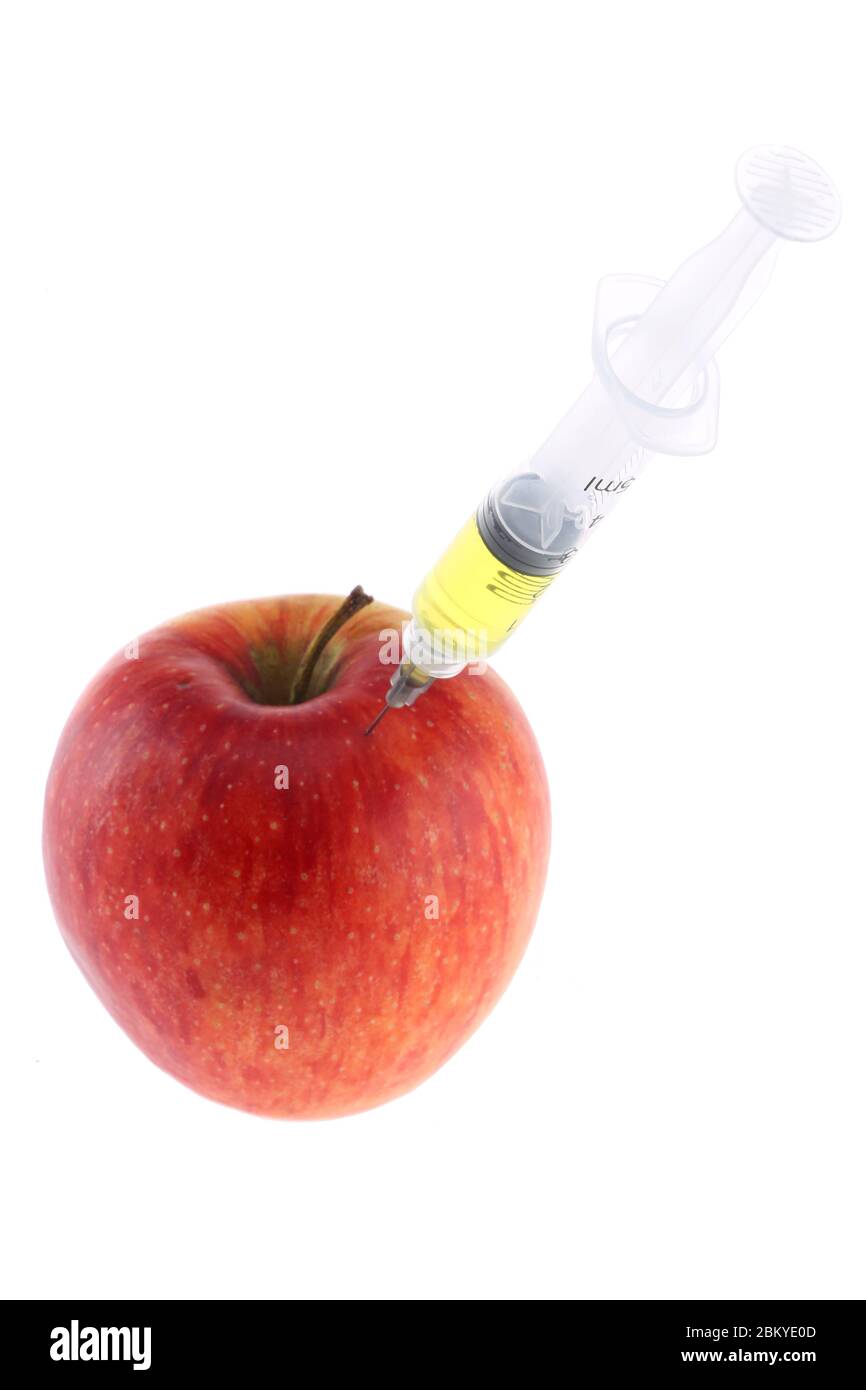 Injektion in einen Apfel. Eine Hand in einem medizinischen Handschuh mit einer Spritze auf weißem Hintergrund. Genetisch veränderte Lebensmittel. Injektion von GVO. Stockfoto