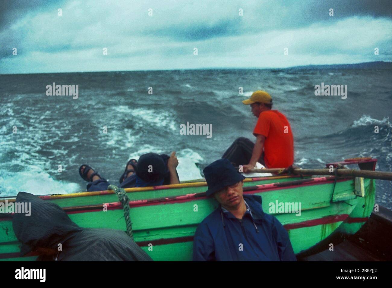 Passagiere und Schiffsbesatzungen schlafen und sitzen auf einem gemieteten Boot, das auf der Sunda-Straße inmitten schlechter Wetterbedingungen segelt und nach dem Verlassen von Peucang Island, einem Teil des Ujung Kulon Nationalparks in Pandeglang, Banten, Indonesien, in die Küstenstadt Sumur fährt. Stockfoto