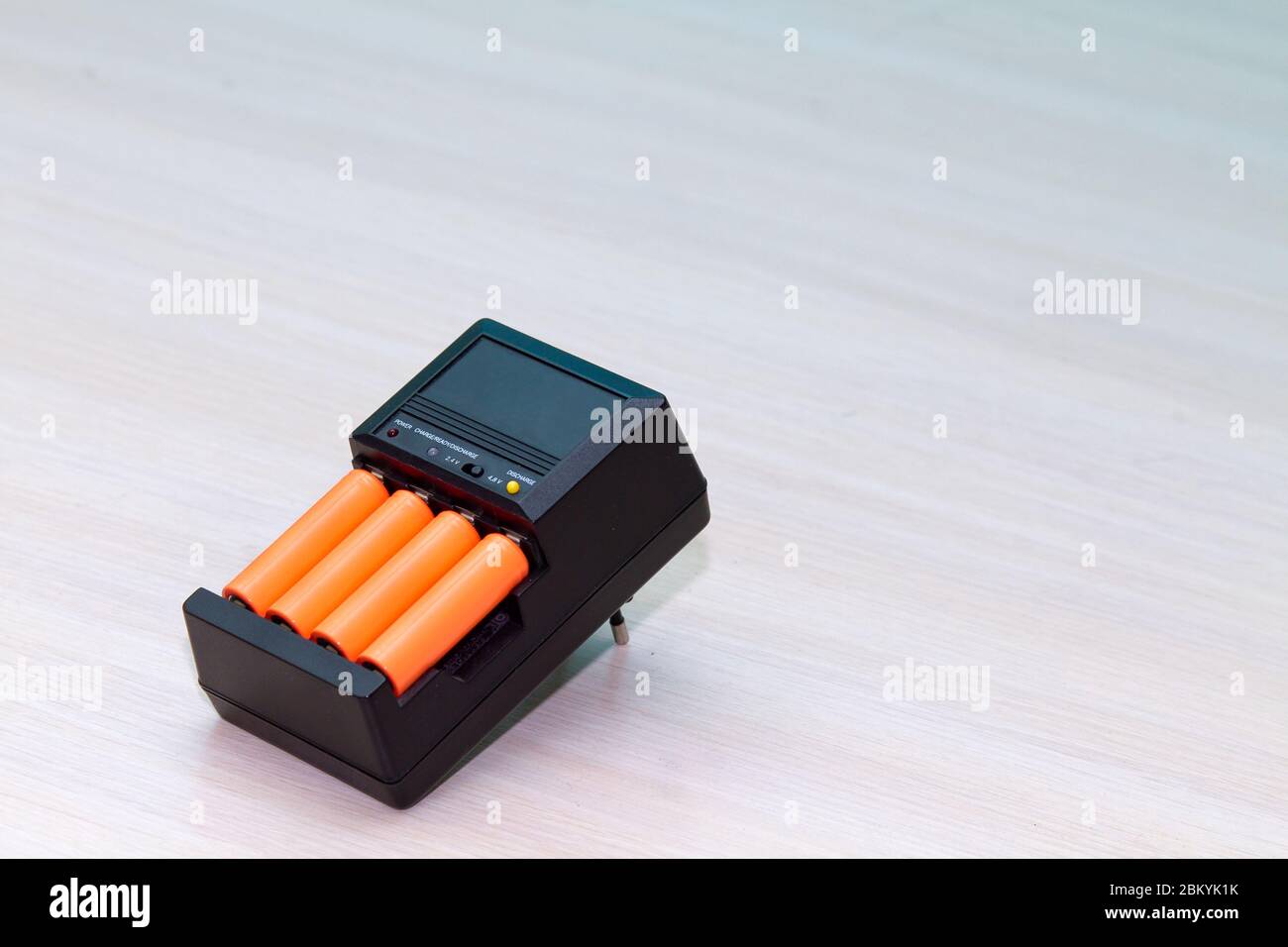 Schwarzes Ladegerät mit orangefarbener AAA-Batterie Stockfoto