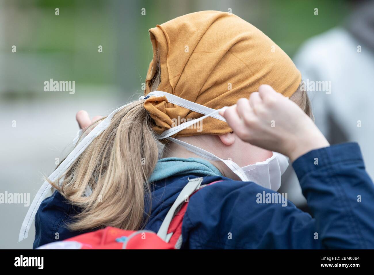 Dresden, Deutschland. Mai 2020. Der Schüler einer vierten Klasse bindet einen Mund- und Nasenprotektor vor der 103. Grundschule 'Unterm Regenbogen'. In den Grund- und Sonderschulen beginnen die Klassen für die vierte Klasse im Freistaat wieder in Übereinstimmung mit den Hygiene- und Fernabstandsregeln. Quelle: Sebastian Kahnert/dpa-Zentralbild/dpa/Alamy Live News Stockfoto