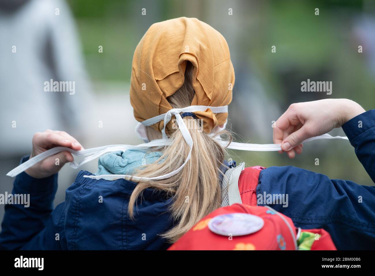 Dresden, Deutschland. Mai 2020. Der Schüler einer vierten Klasse bindet einen Mund- und Nasenprotektor vor der 103. Grundschule 'Unterm Regenbogen'. In den Grund- und Sonderschulen beginnen die Klassen für die vierte Klasse im Freistaat wieder in Übereinstimmung mit den Hygiene- und Fernabstandsregeln. Quelle: Sebastian Kahnert/dpa-Zentralbild/dpa/Alamy Live News Stockfoto