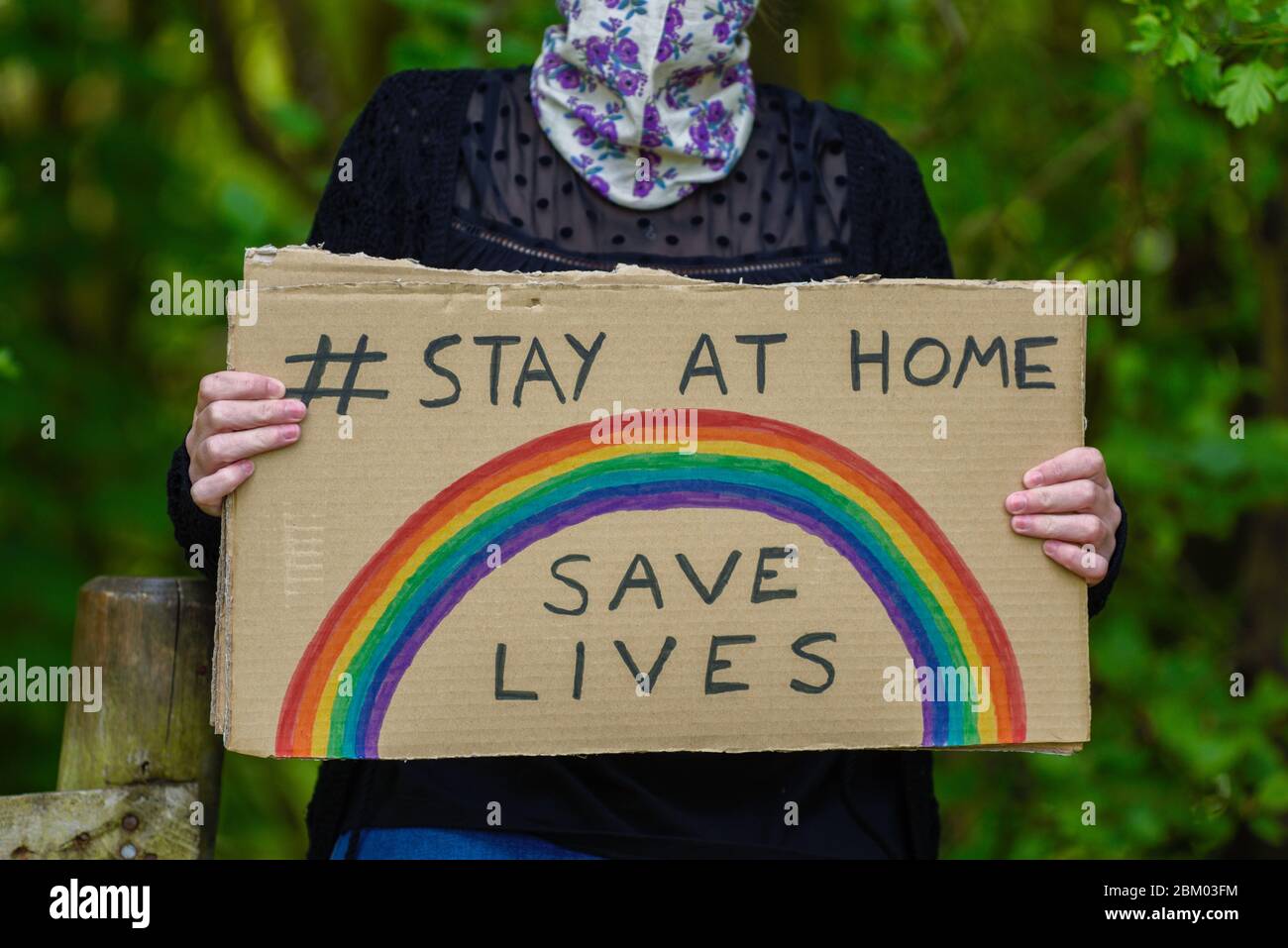 Junge Frauen, die ein Schild aus Pappe halten, bleiben zu Hause und retten während der Coronavirus-Pandemie Leben. Stockfoto