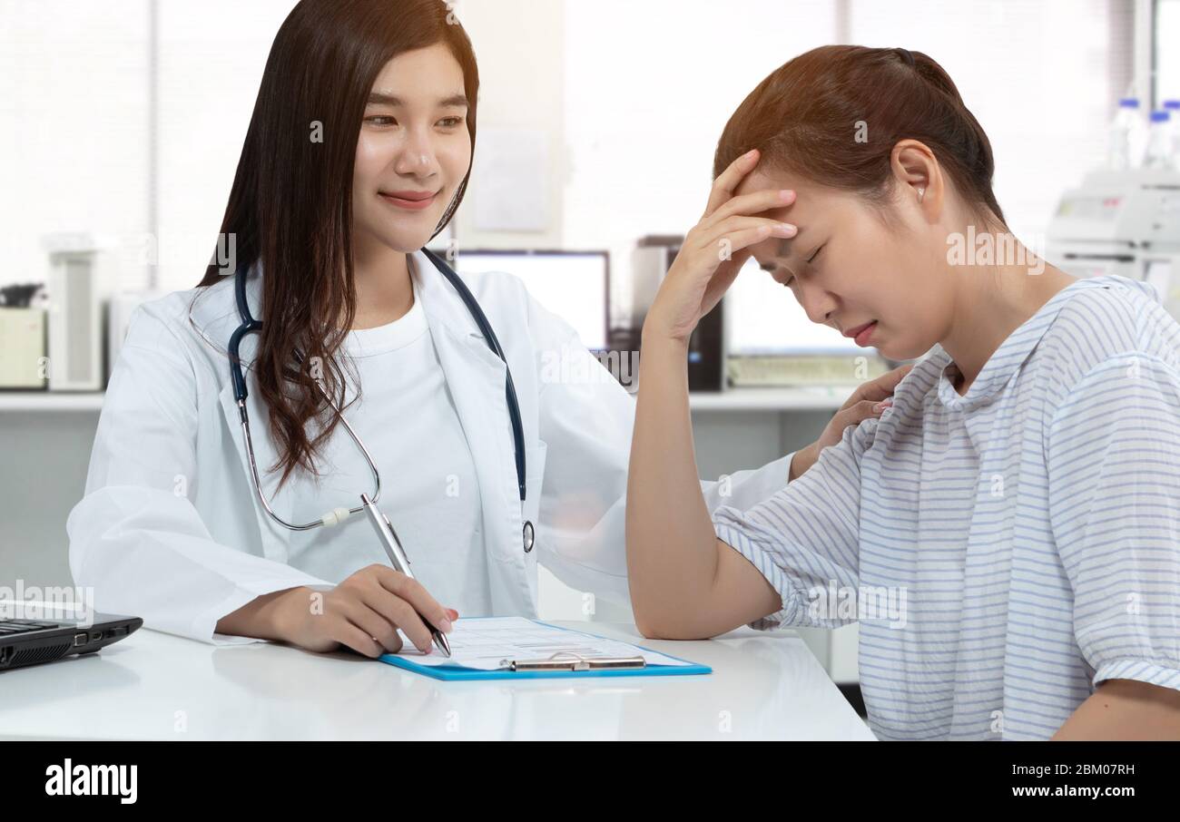 Freundliche asiatische Arzt mit Smiley Gesicht, berühren Stress Patienten auf der Schulter für beruhigen mit sanft ruhig in medizinischen Sprechzimmer. Unterstützende Menta Stockfoto
