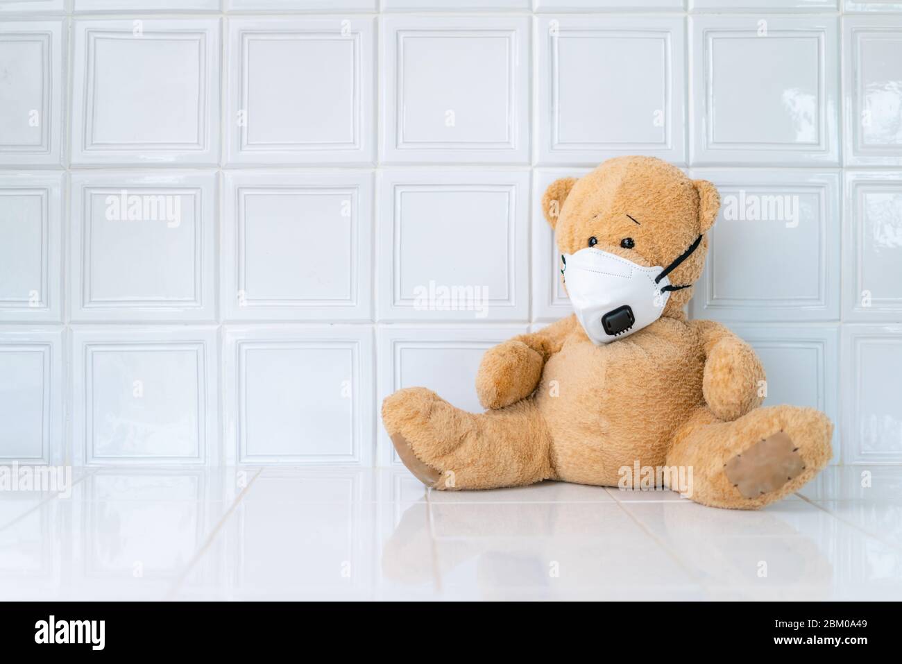 Teddybär mit Gesichtsmaske auf weißem Hintergrund. Konzept der Heimschule, Isolation. Zu Hause bleiben. Corona-Virus. Stockfoto