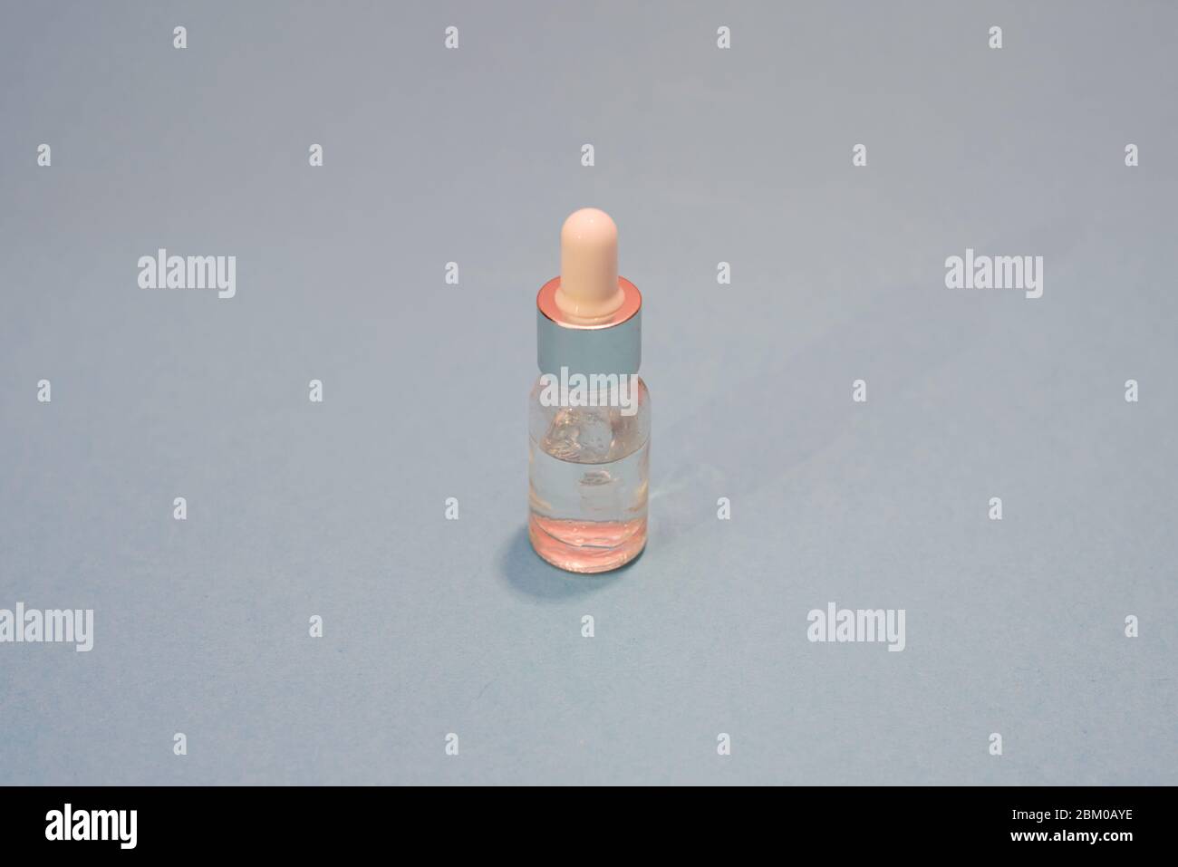 Eine Kosmetikflasche mit rosa Licht auf blauem Hintergrund. Natürliche Schönheit. Platz für Text. Stockfoto