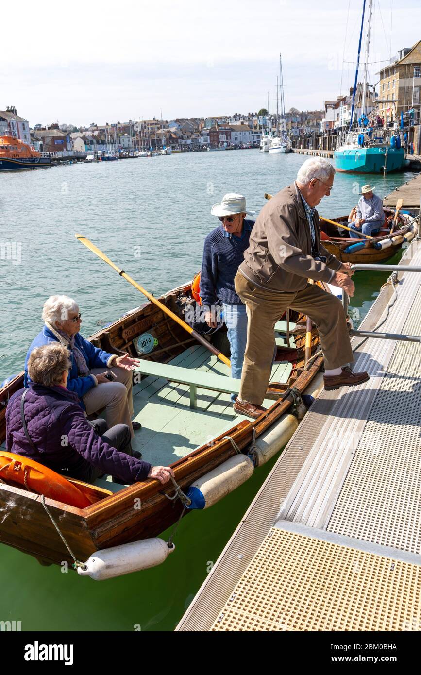 Weymouth, Dorset, England, Großbritannien um 2014. Ältere Menschen genießen eine Fahrt über den Hafen von Weymouth mit einer Ruderbootfähre. Stockfoto