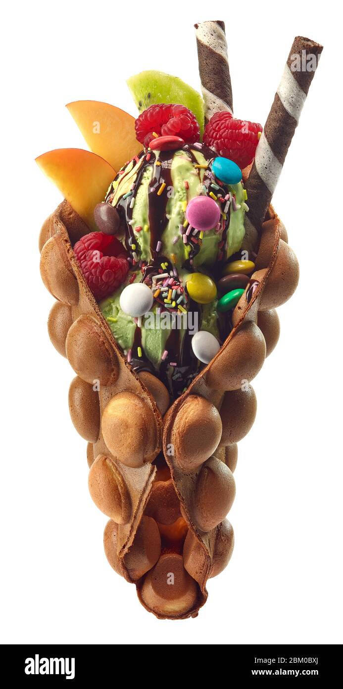 Hong kong oder Bubble Waffel mit Eis, Obst und bunten Süßigkeiten auf weißem Hintergrund isoliert Stockfoto