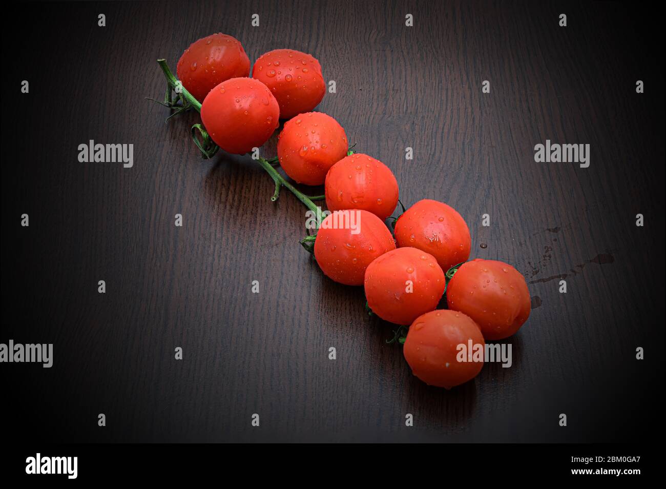 Frische Kirsche oder Mini-Tomaten auf einem Ast auf einem Tisch. Niedrige Tomaten. Stockfoto