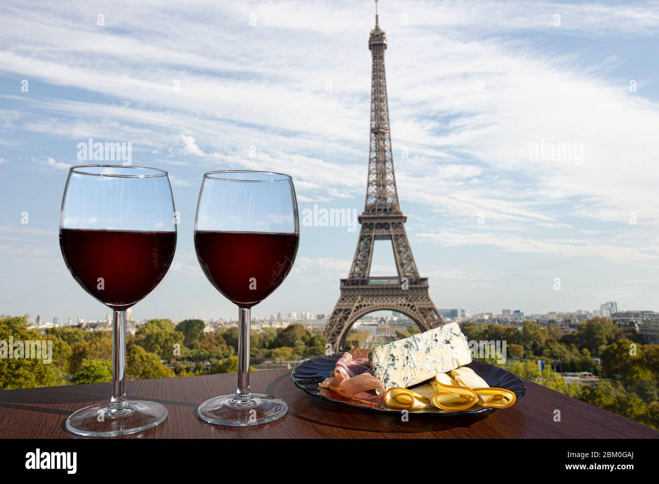 Zwei Gläser Rotwein mit Wurstwaren auf Sicht von Paris und dem Eiffelturm. Ein Glas Rotwein mit verschiedenen Snacks - Teller. Stockfoto