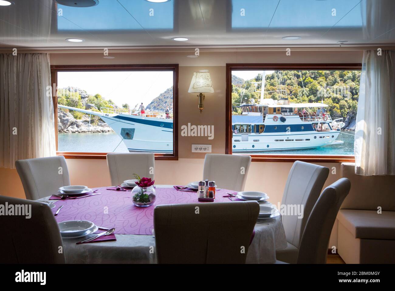 Innen eines Restaurants Tisch mit Blick auf ein Touristenschiff durch das Fenster Stockfoto