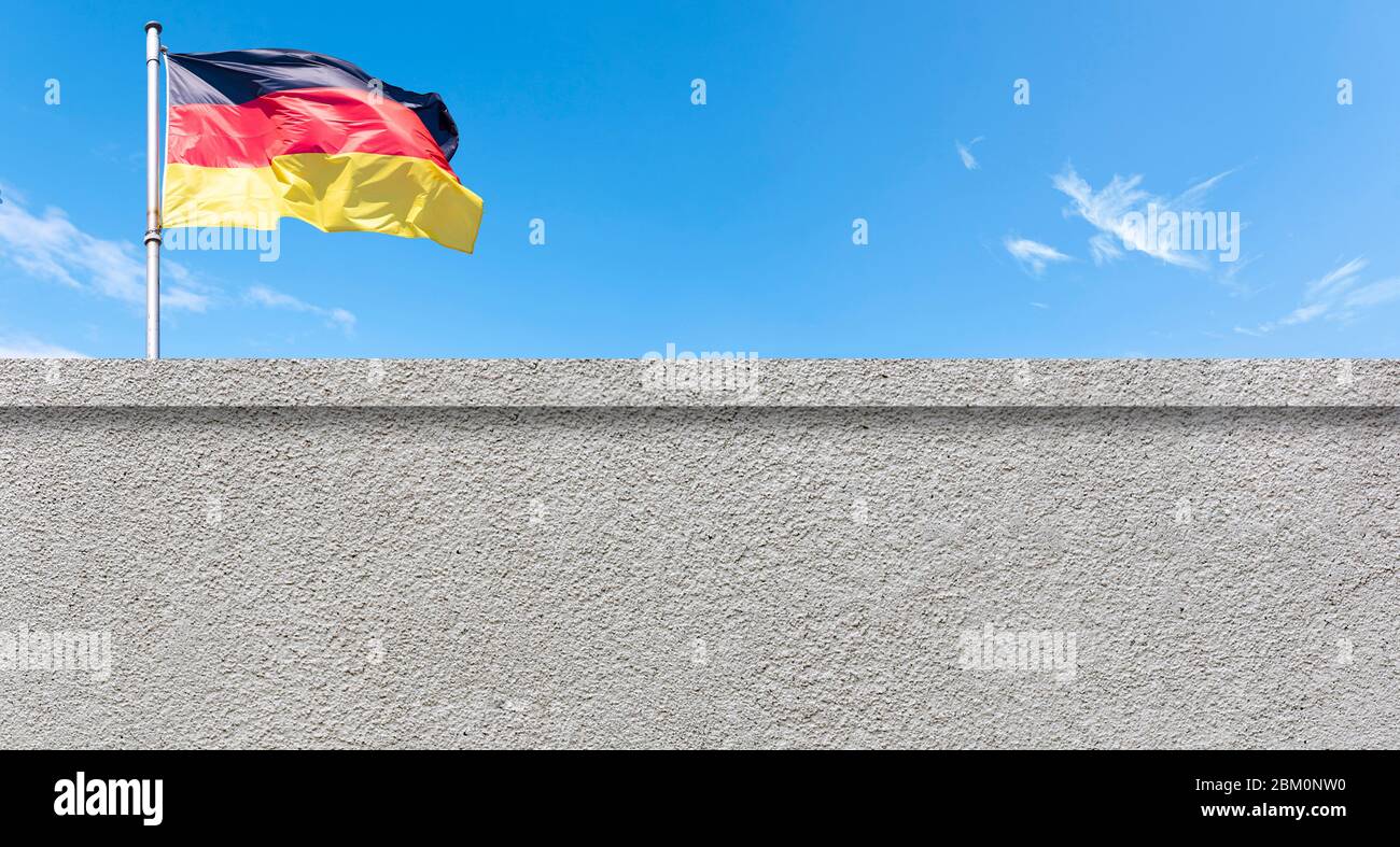 Berliner Mauer, Berliner Grenze und Flagge Deutschlands gegen blauen Himmel Stockfoto