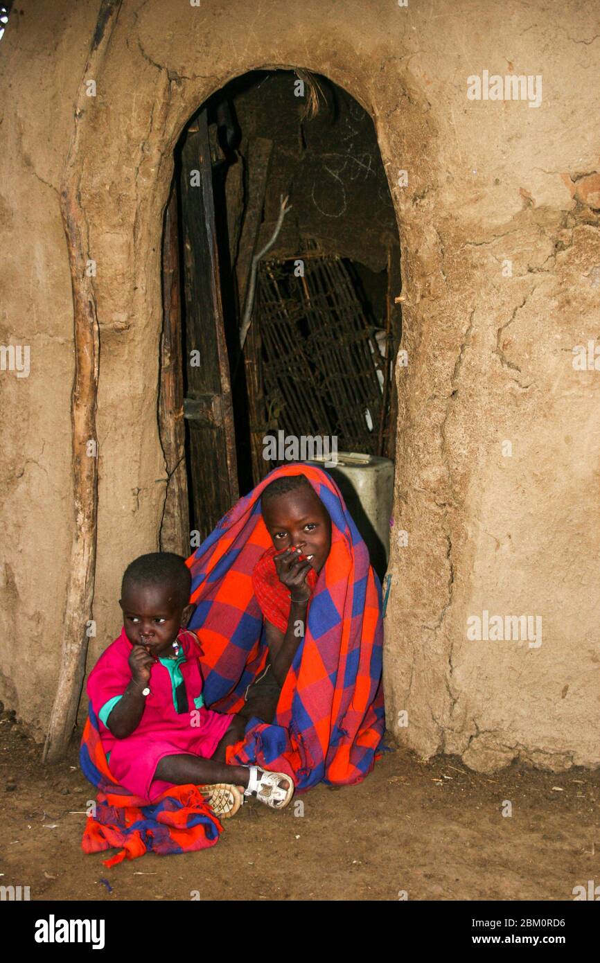 Kleines Maasai-Kind am Eingang zu einer Hütte. Maasai ist eine ethnische Gruppe von halbnomadischen Menschen, die in Kenia fotografiert wurden Stockfoto