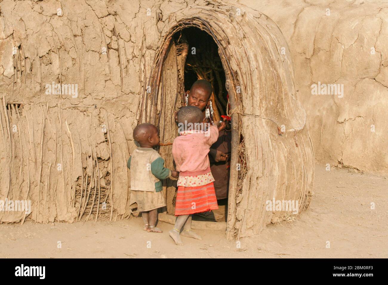 Kleines Maasai-Kind am Eingang zu einer Hütte. Maasai ist eine ethnische Gruppe von halbnomadischen Menschen, die in Kenia fotografiert wurden Stockfoto